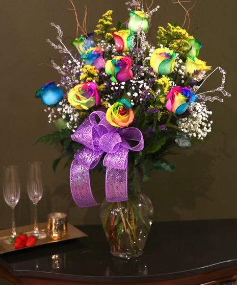 Twelve rainbow roses in a clear glass vase.