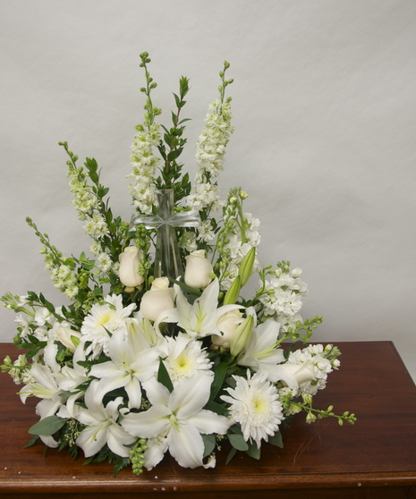Keepsake crystal cross surrounded by white flowers in a sympathy arrangement