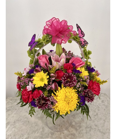 Basket filled with spray roses, carnations, heather and more topped with butterfly decorations.