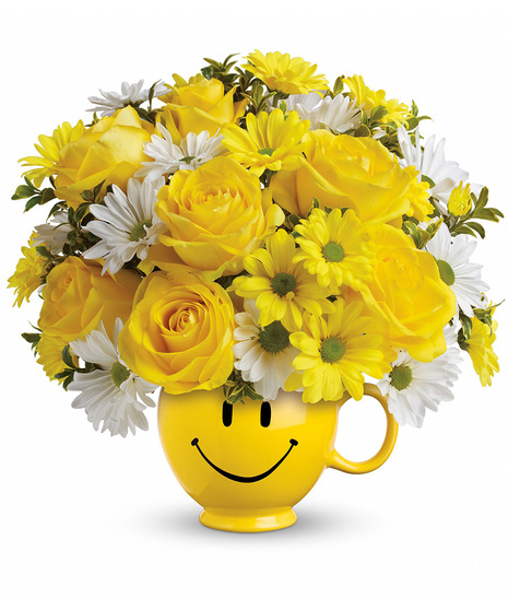 Smiley face mug full of roses and daisies.