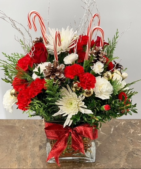 Cube vase of red and white flowers, winter greenery and candy canes