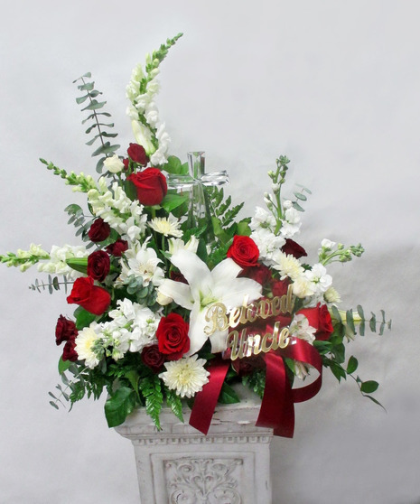 Keepsake crystal cross surrounded by white flowers in a sympathy arrangement