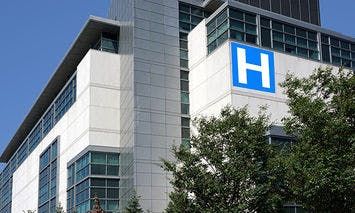 A modern multi-story hospital building displays a large blue 